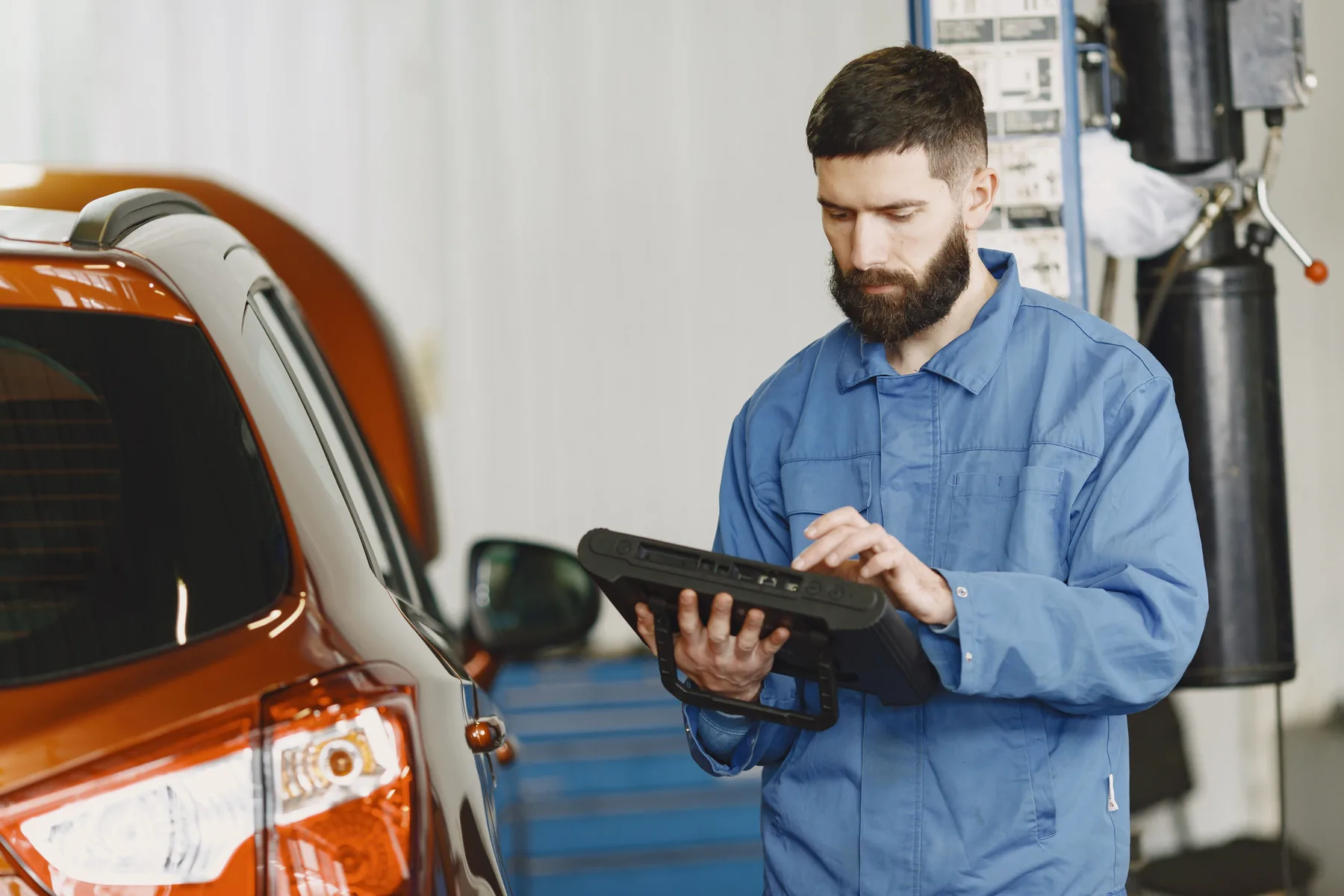 Mechaniker bedient ein Diagnosegerät neben einem Fahrzeug